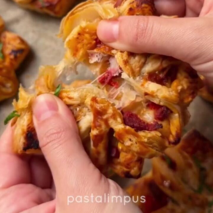 Golden puff pastry pizza flowers with sucuk and peppers on a baking sheet