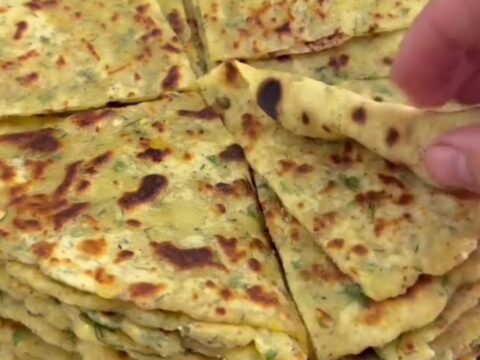 Stack of golden-brown potato cheese flatbreads brushed with butter, one torn open showing melted cheese