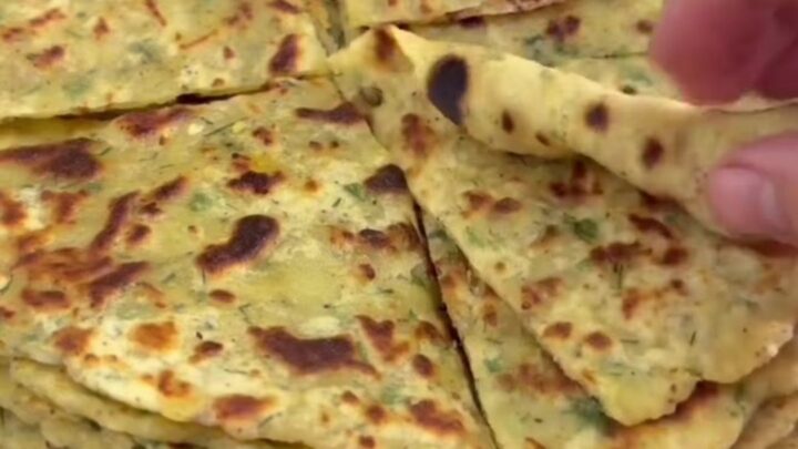 Stack of golden-brown potato cheese flatbreads brushed with butter, one torn open showing melted cheese