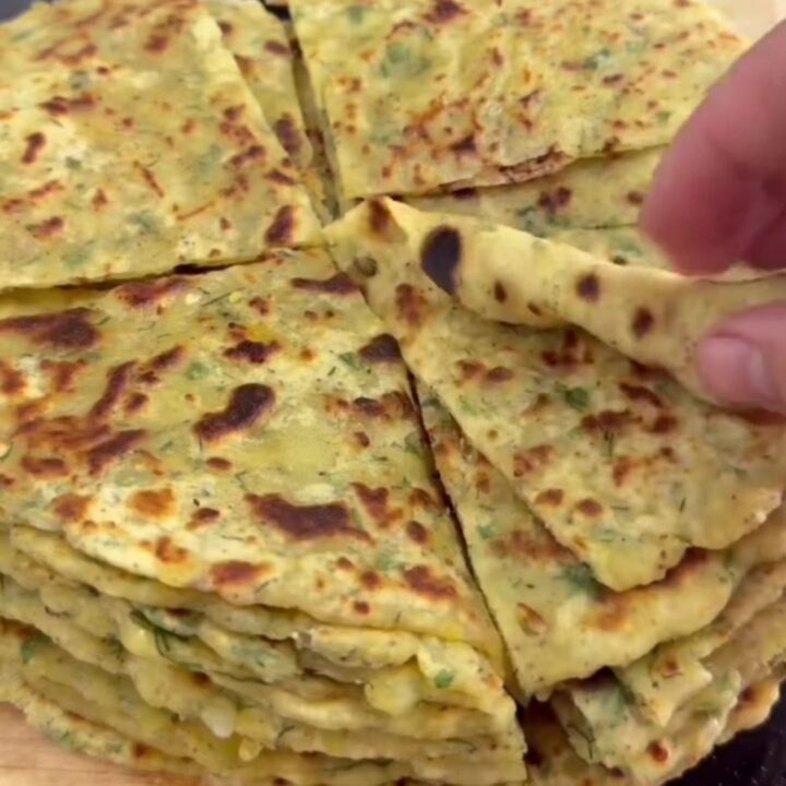 Stack of golden-brown potato cheese flatbreads brushed with butter, one torn open showing melted cheese