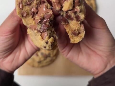 Thick six-ounce chocolate chip cookie broken open showing molten chocolate center