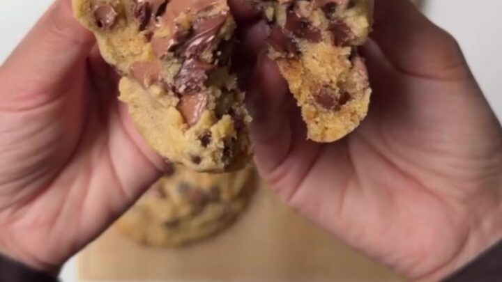Thick six-ounce chocolate chip cookie broken open showing molten chocolate center