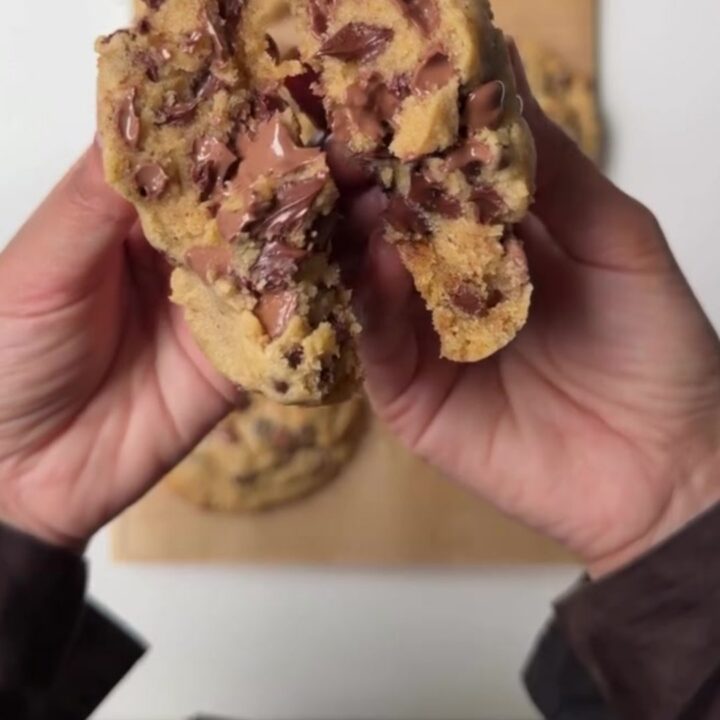 Thick six-ounce chocolate chip cookie broken open showing molten chocolate center