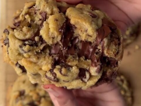 Thick chocolate chip cookie broken in half with molten chocolate pulling apart