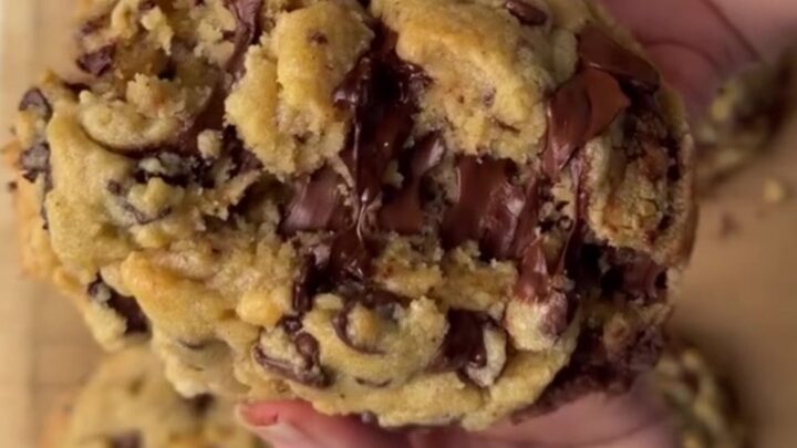 Thick chocolate chip cookie broken in half with molten chocolate pulling apart