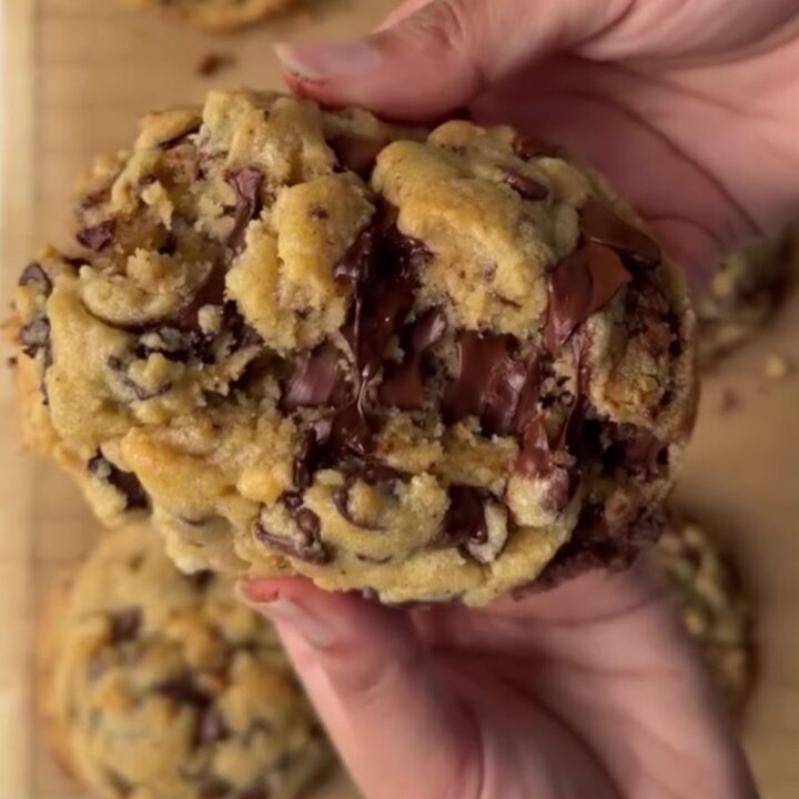 Thick chocolate chip cookie broken in half with molten chocolate pulling apart