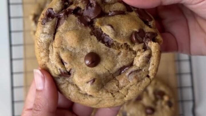 A stack of brown butter chocolate chip cookies with gooey melted chocolate centers on a cooling rack.