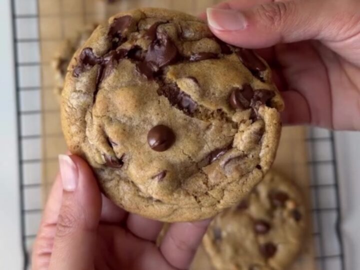 A stack of brown butter chocolate chip cookies with gooey melted chocolate centers on a cooling rack.
