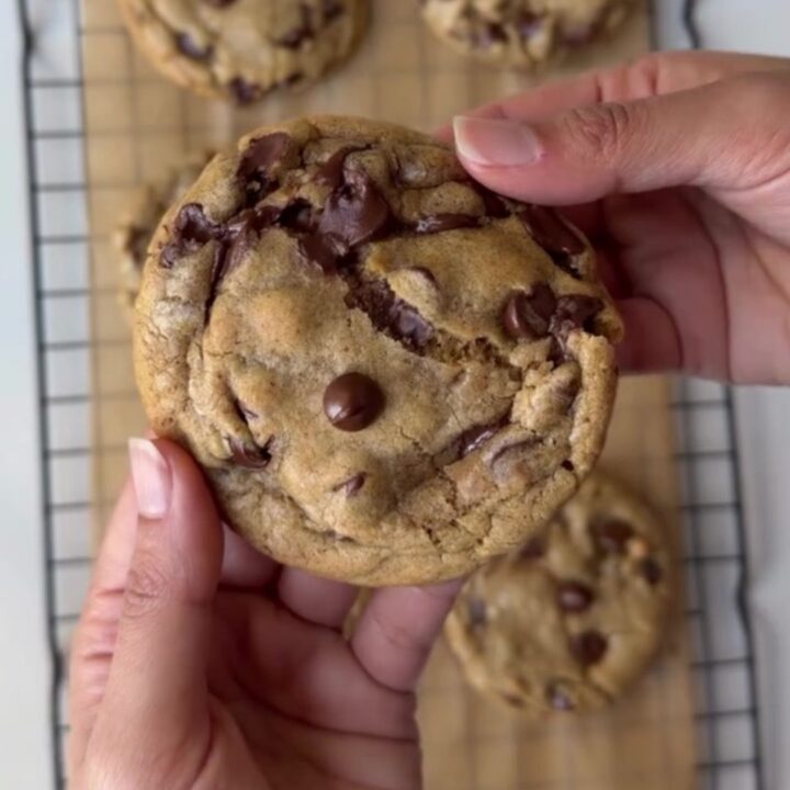 A stack of brown butter chocolate chip cookies with gooey melted chocolate centers on a cooling rack.
