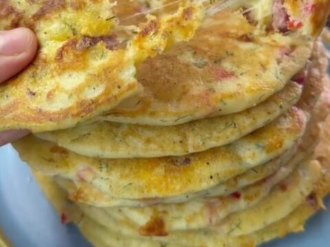 A stack of thick golden Turkish breakfast crepes with melted cheese pulling as one is torn apart