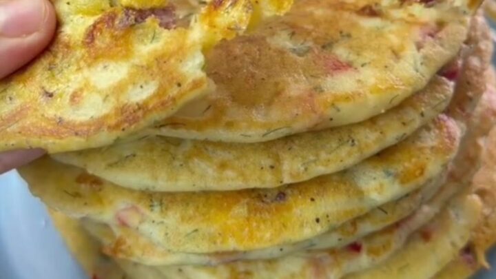 A stack of thick golden Turkish breakfast crepes with melted cheese pulling as one is torn apart