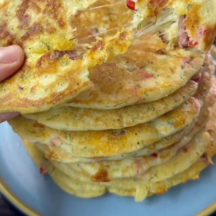 A stack of thick golden Turkish breakfast crepes with melted cheese pulling as one is torn apart