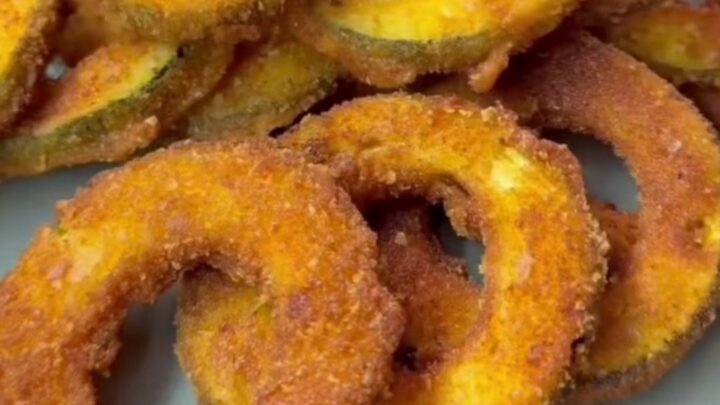 Crispy golden zucchini rings with a crunchy breadcrumb crust, served with a bowl of creamy garlic yogurt for dipping.