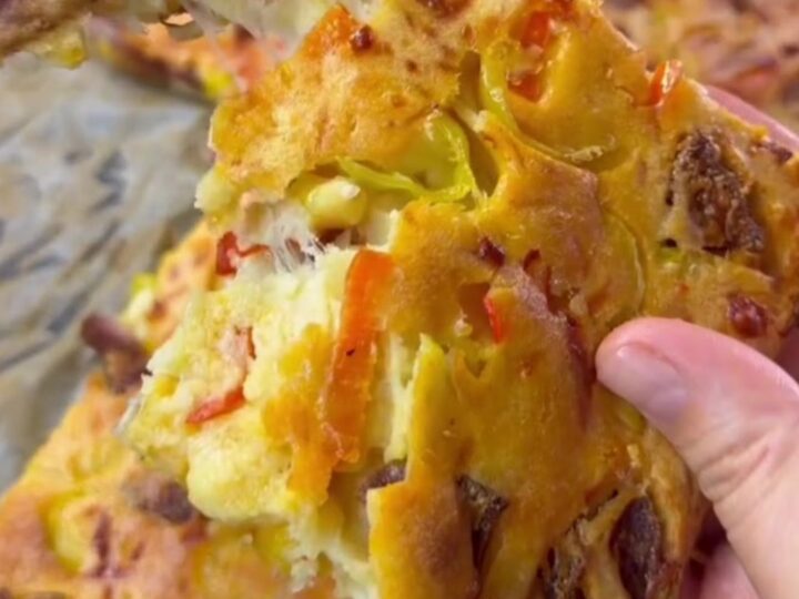 Golden sheet pan crepe pizza topped with sucuk, corn, peppers, and melted mozzarella, cut into squares