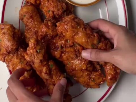 Crispy honey sriracha chicken tenders glazed and garnished with sesame seeds and scallions