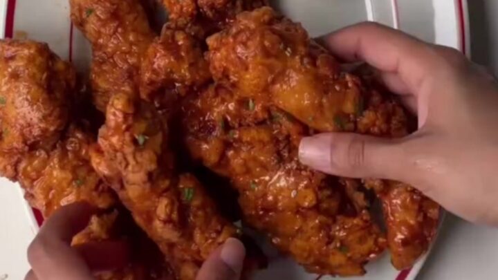 Crispy honey sriracha chicken tenders glazed and garnished with sesame seeds and scallions