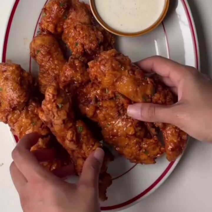 Crispy honey sriracha chicken tenders glazed and garnished with sesame seeds and scallions