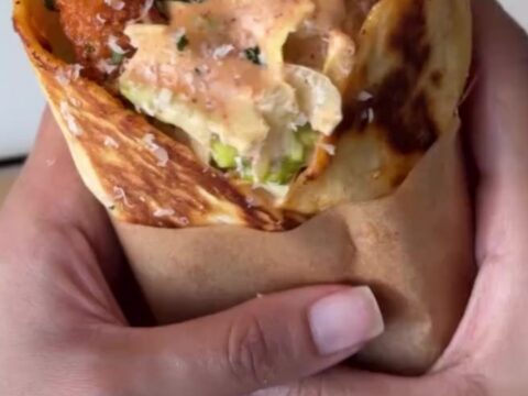 Crispy chicken Caesar wrap sliced diagonally, showing crunchy chicken, romaine, and parmesan.