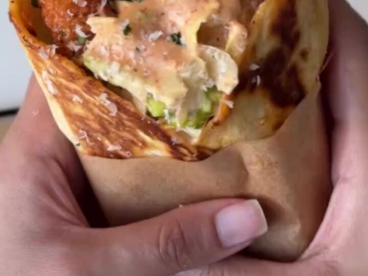 Crispy chicken Caesar wrap sliced diagonally, showing crunchy chicken, romaine, and parmesan.