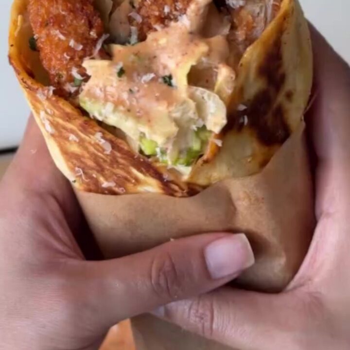 Crispy chicken Caesar wrap sliced diagonally, showing crunchy chicken, romaine, and parmesan.