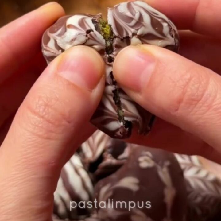 Chocolate-dipped dates with marbled white chocolate hearts on parchment paper