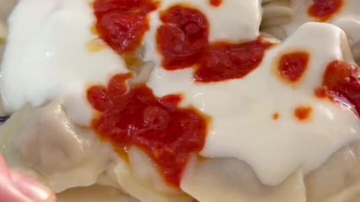Steaming manti dumplings in a bowl topped with garlic yogurt and sizzling Aleppo pepper butter