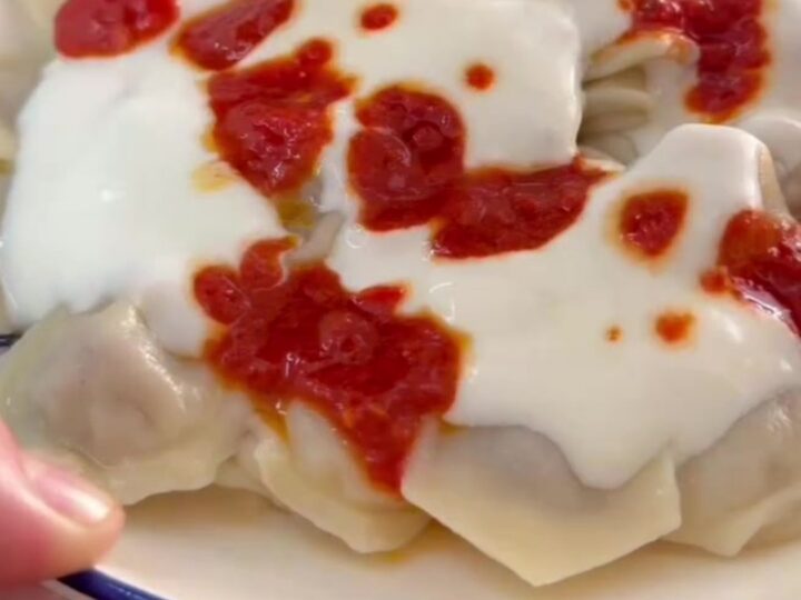 Steaming manti dumplings in a bowl topped with garlic yogurt and sizzling Aleppo pepper butter