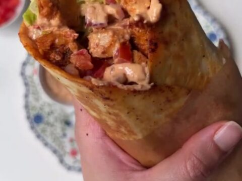 Crispy chipotle chicken burrito sliced in half showing layers of chicken, lettuce, and melted cheese