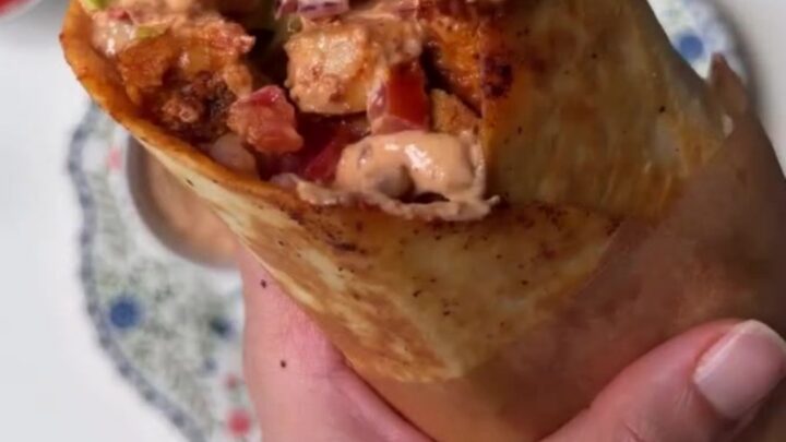 Crispy chipotle chicken burrito sliced in half showing layers of chicken, lettuce, and melted cheese