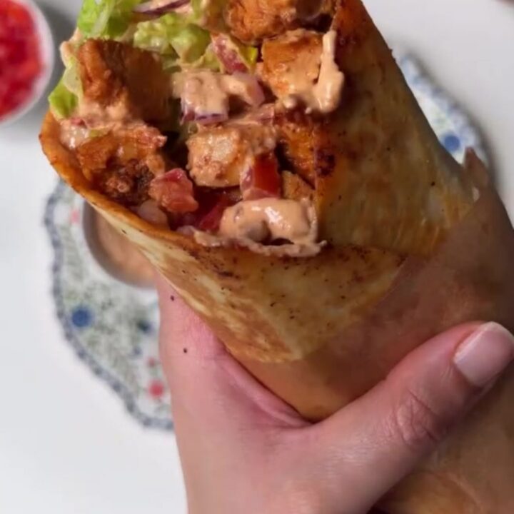 Crispy chipotle chicken burrito sliced in half showing layers of chicken, lettuce, and melted cheese