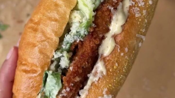 A crispy fried chicken Caesar sandwich on a toasted brioche bun, sliced in half
