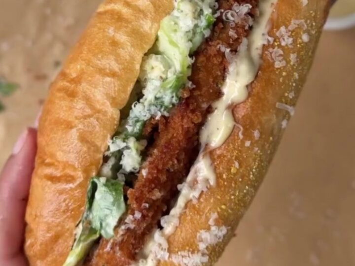 A crispy fried chicken Caesar sandwich on a toasted brioche bun, sliced in half