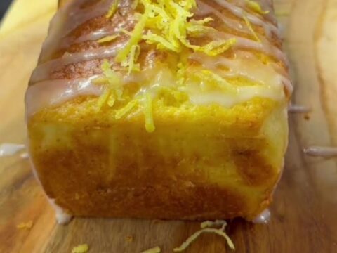 Sliced lemon cake with white glaze zigzags on a cutting board