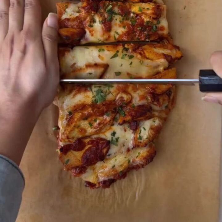 Loaded baguette with bubbling mozzarella and butter chicken, sliced to show cheese pull