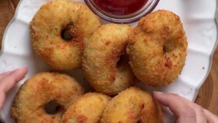 Golden fried doughnut being torn open with stretchy mozzarella cheese pull