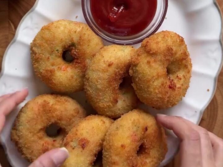 Golden fried doughnut being torn open with stretchy mozzarella cheese pull