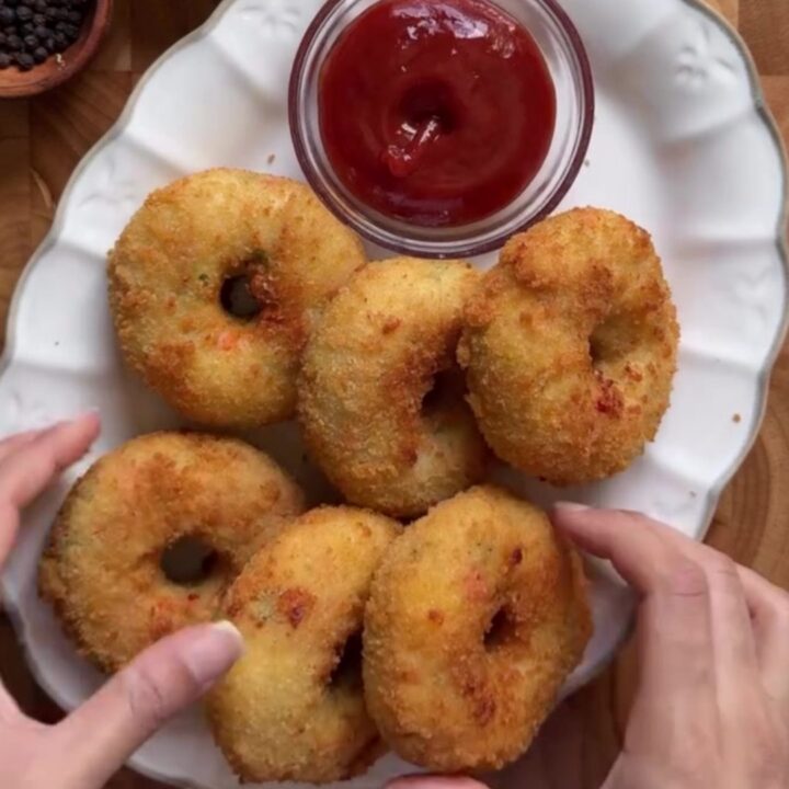 Golden fried doughnut being torn open with stretchy mozzarella cheese pull