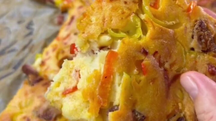 Savory sucuk breakfast sheet cake with melted cheese, sliced into squares on a baking pan