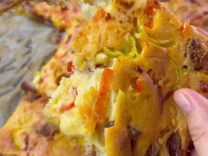 Savory sucuk breakfast sheet cake with melted cheese, sliced into squares on a baking pan