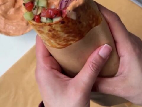 Crispy chicken kebab wrap sliced diagonally, showing juicy charred chicken, garlic sauce, and sumac pickles.