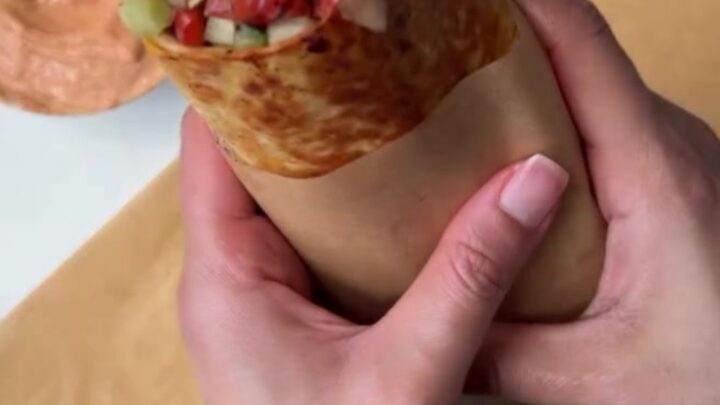 Crispy chicken kebab wrap sliced diagonally, showing juicy charred chicken, garlic sauce, and sumac pickles.