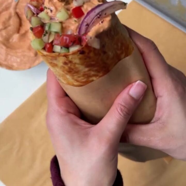 Crispy chicken kebab wrap sliced diagonally, showing juicy charred chicken, garlic sauce, and sumac pickles.