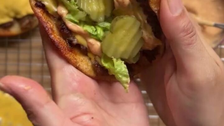 Crispy smash burger taco with melted cheese, shredded lettuce, pickles, and secret sauce, folded in half.
