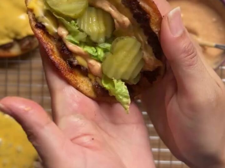 Crispy smash burger taco with melted cheese, shredded lettuce, pickles, and secret sauce, folded in half.