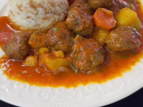 A bowl of Turkish meatball stew with carrots, potatoes, and fresh parsley garnish.