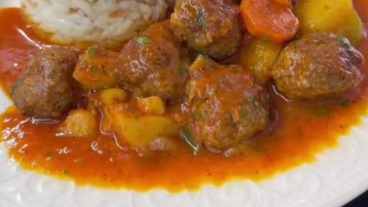 A bowl of Turkish meatball stew with carrots, potatoes, and fresh parsley garnish.