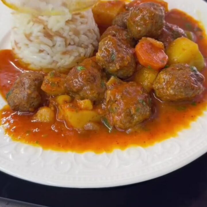 A bowl of Turkish meatball stew with carrots, potatoes, and fresh parsley garnish.