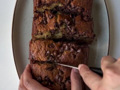 Warm slice of banana bread with melty chocolate pools on a wooden board