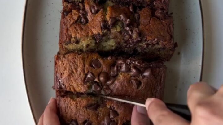Warm slice of banana bread with melty chocolate pools on a wooden board