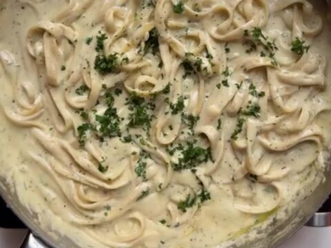 Fettuccine twirled on a fork, coated in a glossy garlic parmesan sauce